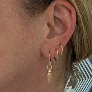 a pair of 14ct gold 12mm sleeper hoops worn in the second and third piercings alongside Edge Only Spiral Drop Earrings and Oval Link Chain