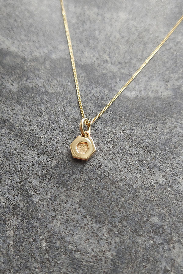 Edge Only Mini Hexagon Pendant in 14 carat recycled gold on marble