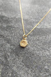 Edge Only Mini Hexagon Pendant in 14 carat recycled gold on marble