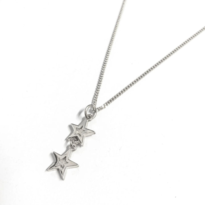 product shot of Edge Only Mini Megastar two Star Pendant in sterling silver. Image shows the thickness of the stars