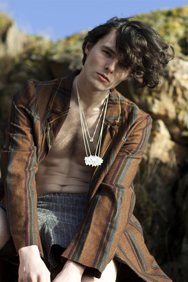 Person wearing a brown jacket with a Edge Only POW! Pendant XL and Hex Nut XL in recycled Sterling Silver  in a natural setting