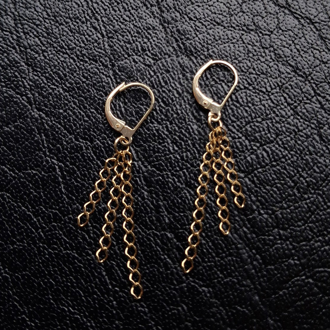 Edge Only Triple Chain Drop Earrings in solid 9ct gold. Lying flat on black leather