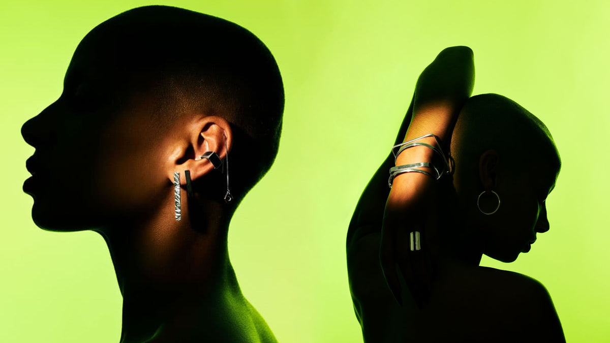 Two silhouetted humans wearing Edge Only silver drop earrings and silver bangles against a bright lime green background.