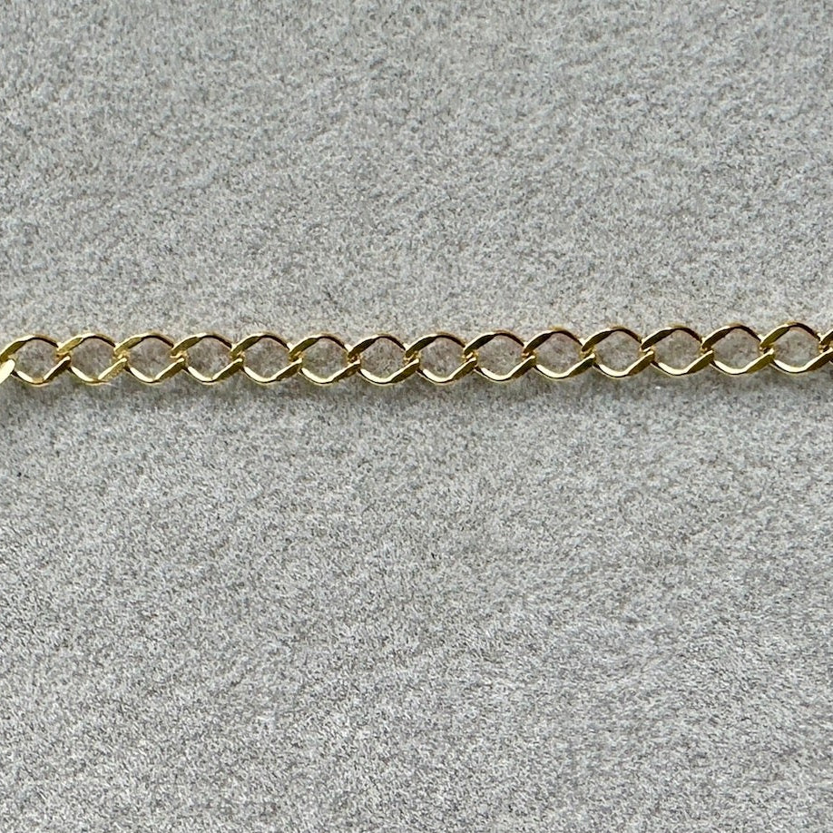 a section of Edge Only 9 carat gold Rombo style chain link on grey velvet. 
