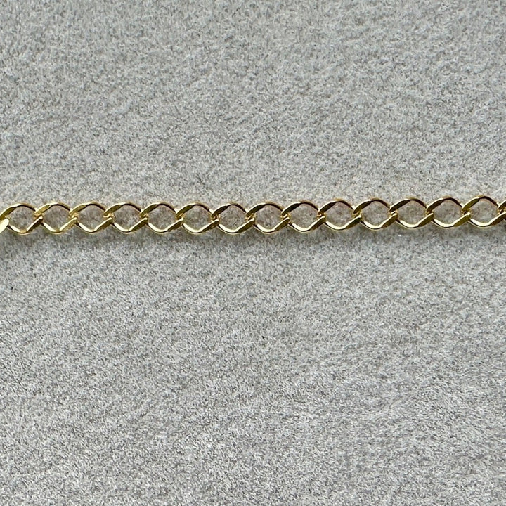 a section of Edge Only 9 carat gold Rombo style chain link on grey velvet. 