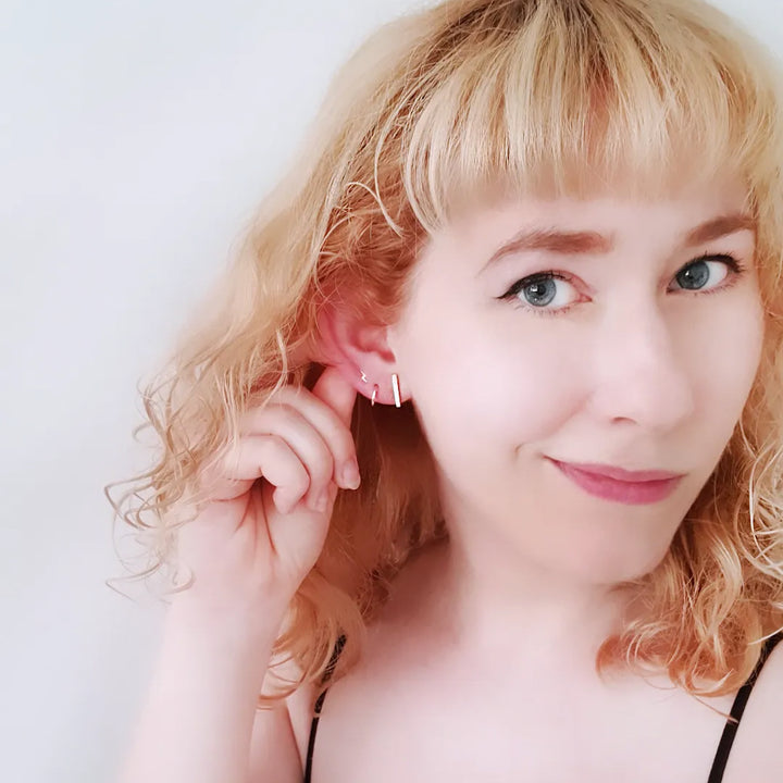 Edge Only Tiny Lightning bolt earring in 14ct gold, Mini hoop earring 9ct gold and bar earring 9ct gold on a model with blond hair 